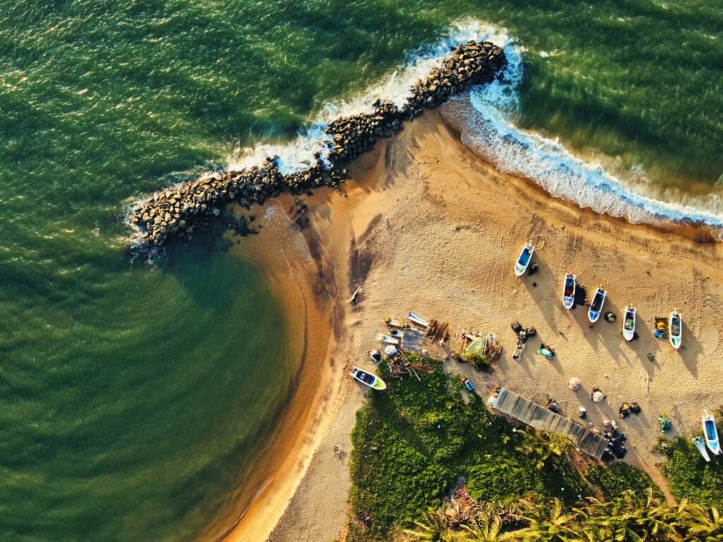 Stunning drone shot of Katuneriya Beach featuring boats, crashing waves, and tetrapods.