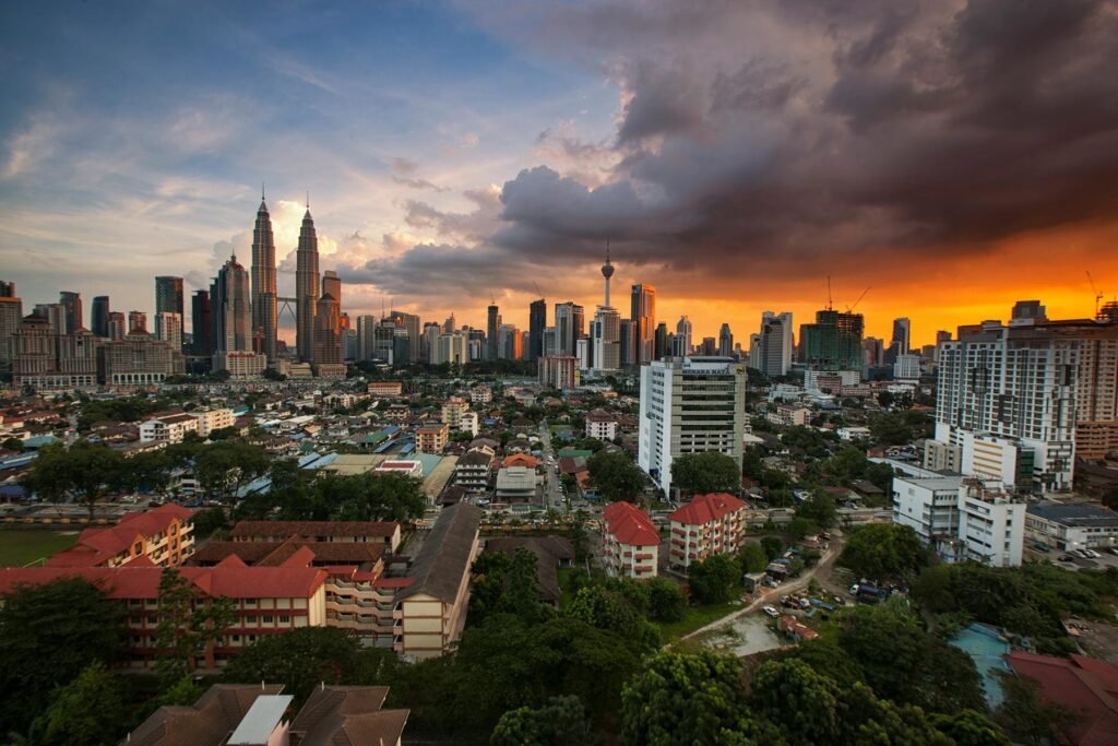 A stunning view of Kuala Lumpur's skyline featuring the Petronas Towers at sunset with vibrant skies.