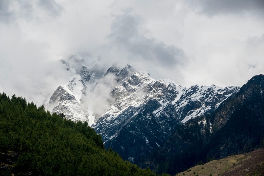 Stunning view of snowcapped mountains surrounded by forests in Kullu, Himachal Pradesh, India.