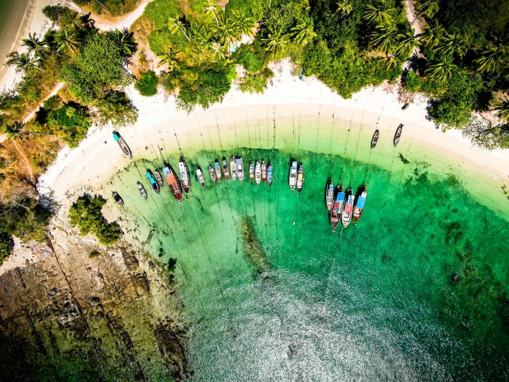 A stunning aerial view capturing boats along the beach at Ko Yao Yai, Thailand, surrounded by lush greenery and turquoise waters.