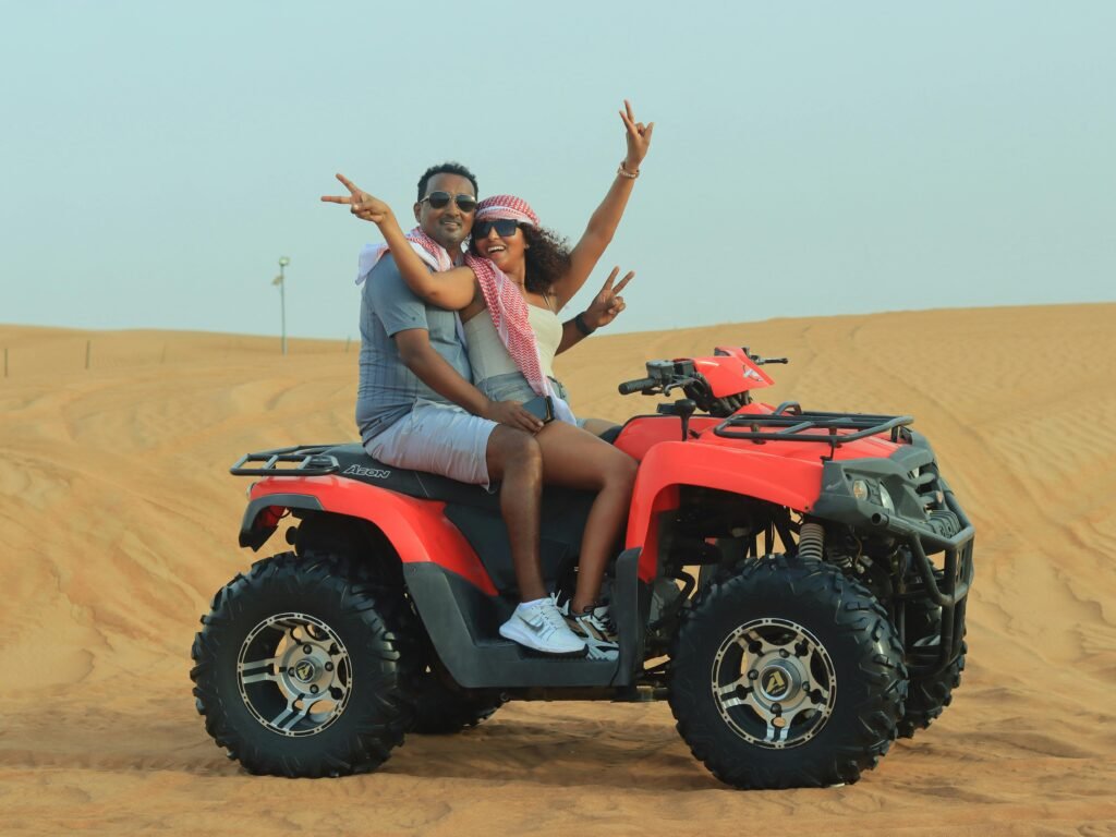 A happy couple enjoys an adventurous quad bike ride in the scenic Dubai desert during the day.