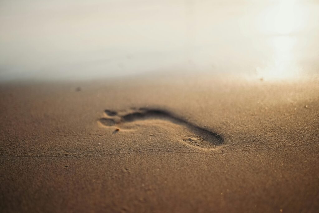 Footprint on sandy beach during sunrise, evoking calm and relaxation.