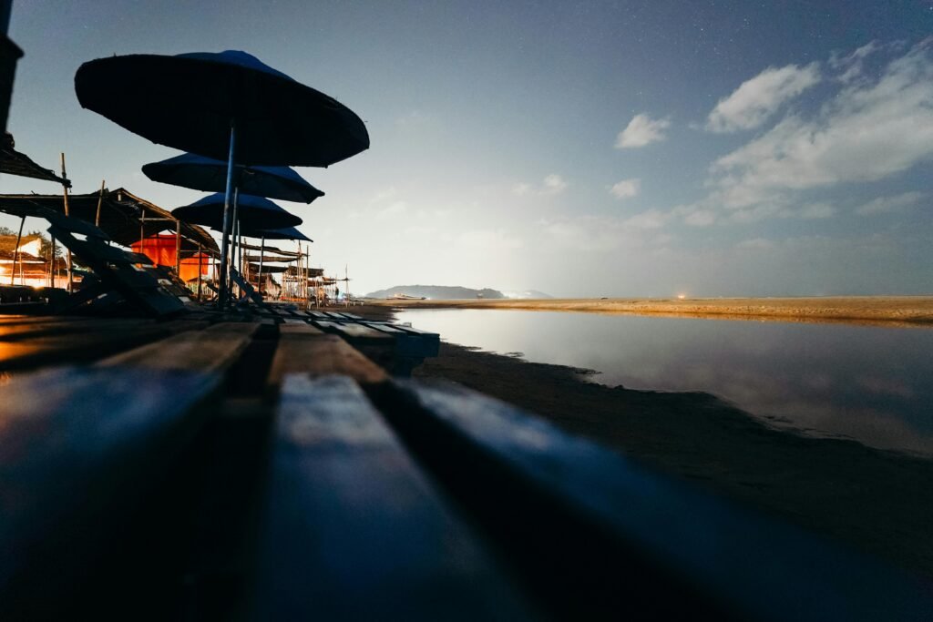 A tranquil beach view at twilight with rows of beach umbrellas and a serene ocean backdrop.