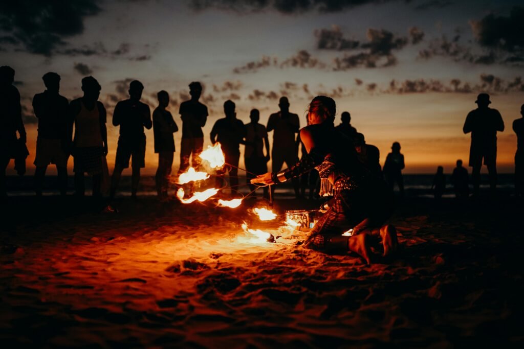 A mesmerizing fire performance on a beach at sunset with a captivated crowd in Goa.