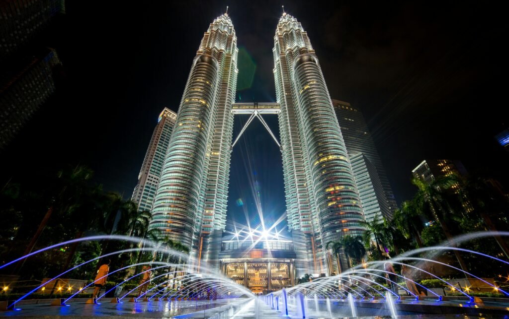 Stunning night view of the illuminated Petronas Twin Towers in Kuala Lumpur with fountains in the foreground.