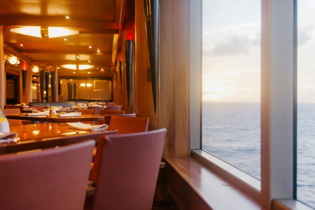 Elegant dining area on a luxury ship overlooking the ocean at sunset, perfect for relaxation.