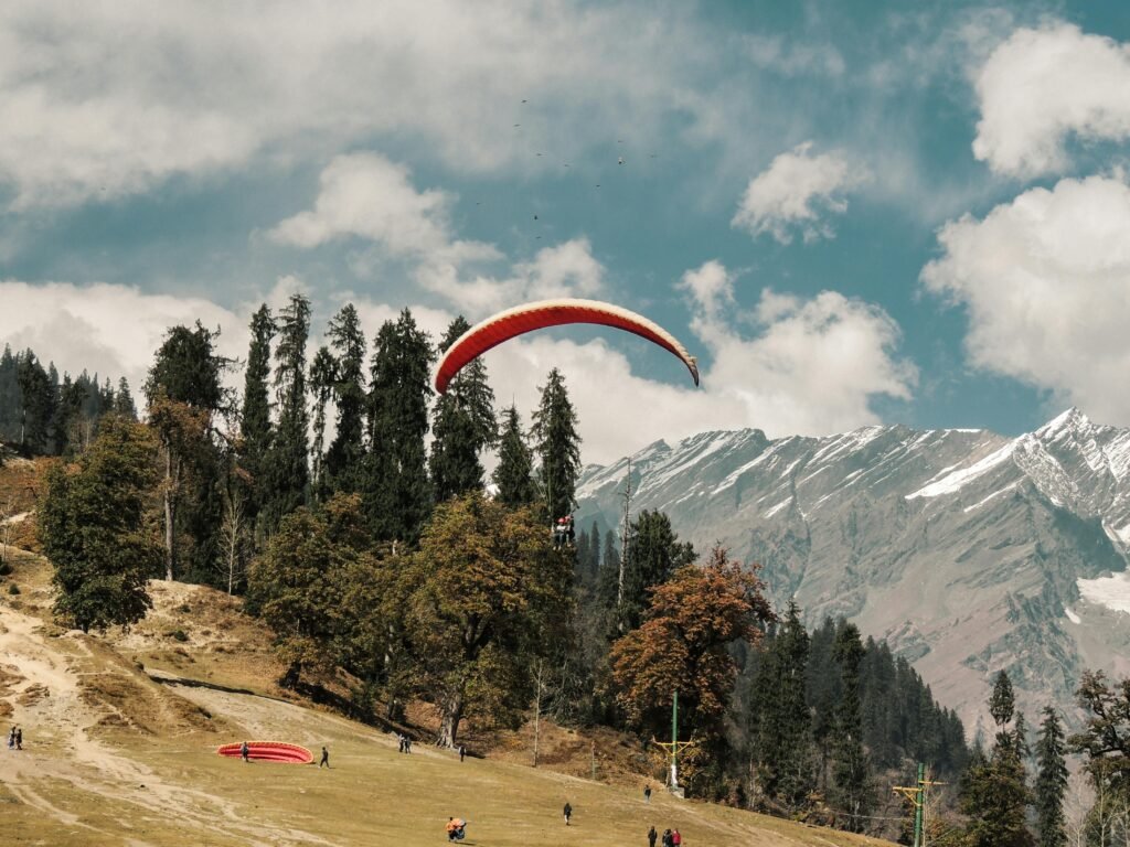 Thrilling paragliding above Manali's scenic landscape with majestic Himalayan mountains.