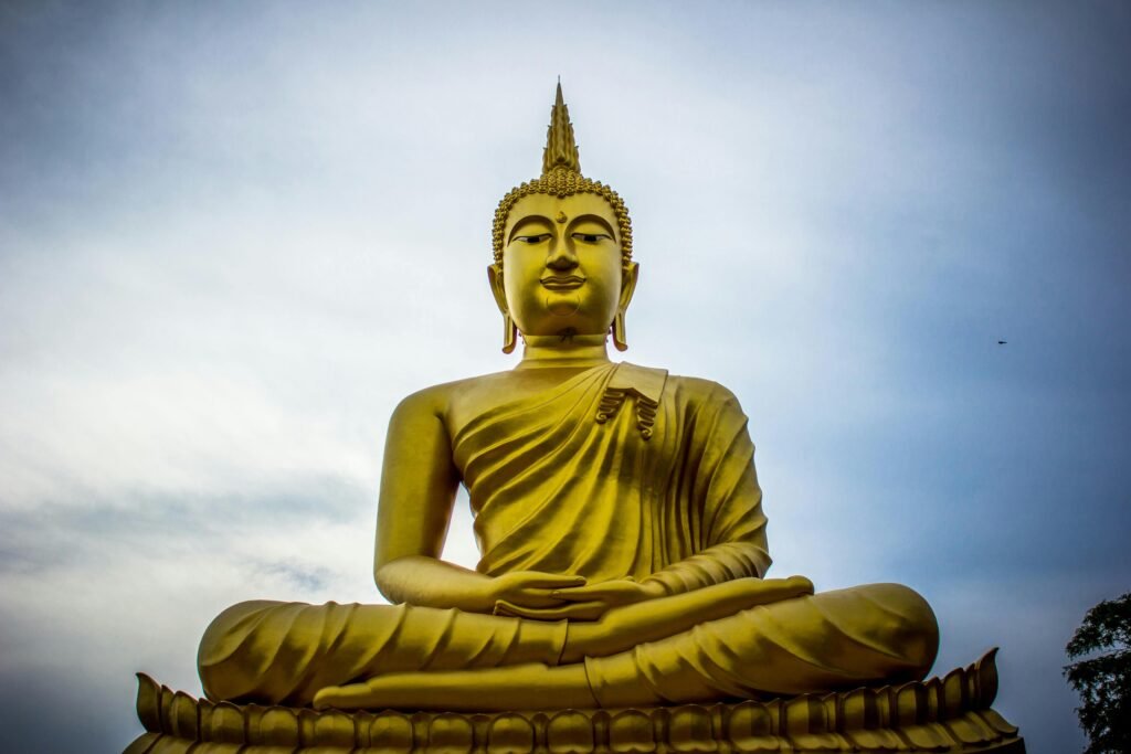 A majestic golden Buddha statue against a serene blue sky, symbolizing peace and spirituality.