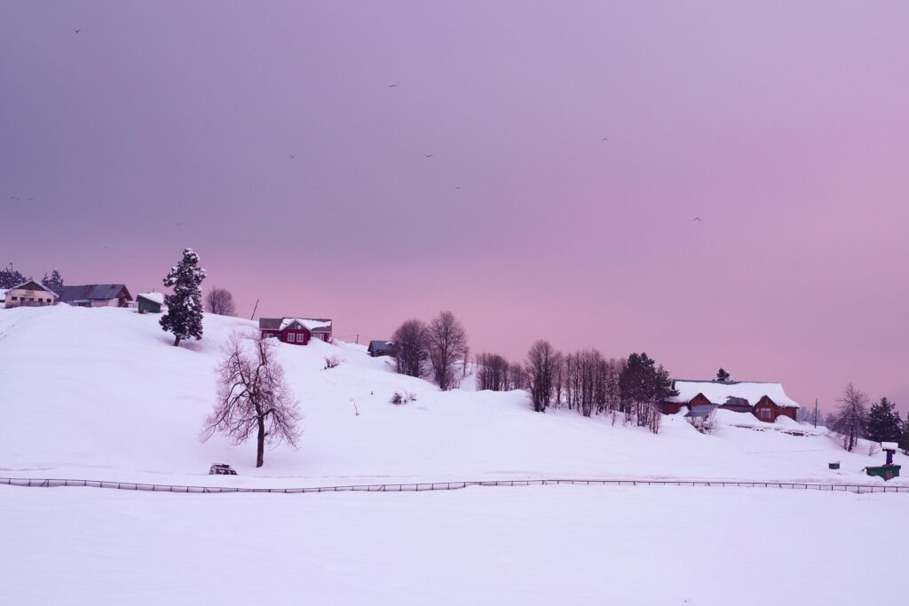 Beautiful snow-covered hills and houses in Gulmarg during a tranquil twilight.