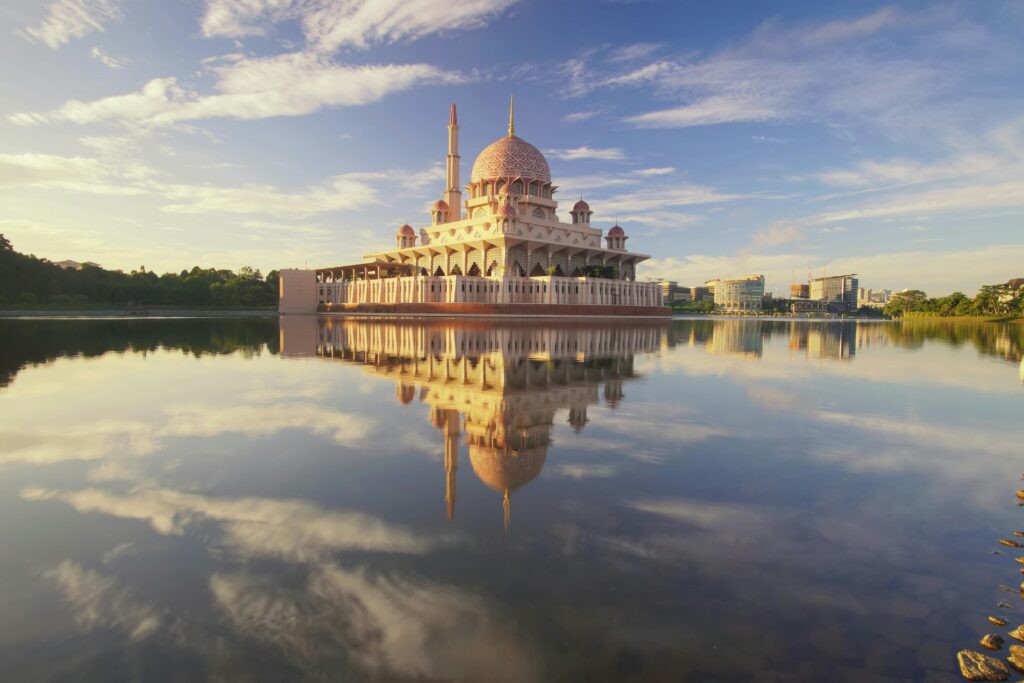 Beautiful scene of Putra Mosque reflecting on calm lake waters under a vibrant morning sky.