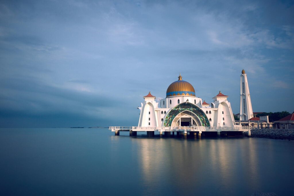 Capture of the majestic Malacca Strait Mosque in serene twilight reflecting upon calm waters.